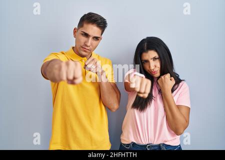 Junges Paar, das über einem isolierten Hintergrund steht und mit Faust kämpft, aggressiver und wütender Angriff, Bedrohung und Gewalt Stockfoto