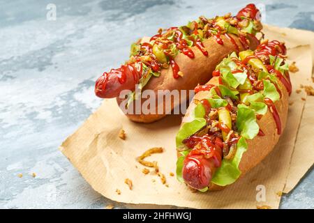 Zwei leckere Hotdogs auf Bastelpapier auf betontem Hintergrund Stockfoto