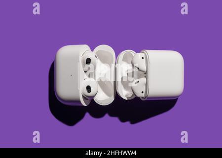 Barcelona, Spanien - Januar 2022. AirPods pro im Vergleich zu Apple Air Pods 2 im kabellosen Ladetasche auf violettem Hintergrund. Kopfhörer, vertikal, Kopie Stockfoto