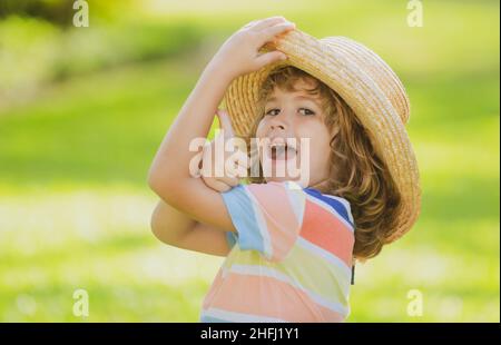 Porträt eines glücklichen lachenden Kindes im Sommer Naturpark mit Daumen nach oben Zeichen. Positive Kinder im Strohhut. Sommerurlaub. Stockfoto