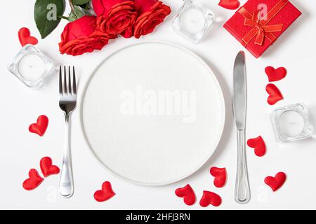 Romantisches Abendessen am Valentinstag Konzept. Wunderschöne Tischeinstellung. Rosen und Kerzen auf weißem Hintergrund. Stockfoto