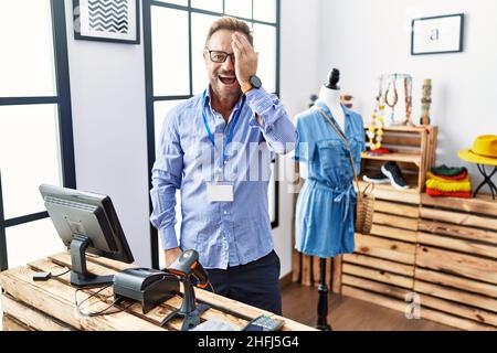 Ein Mann mittleren Alters, der als Manager in einer Einzelhandelsboutique arbeitet, deckt ein Auge mit der Hand, lächelt selbstbewusst im Gesicht und überrascht Emotionen. Stockfoto