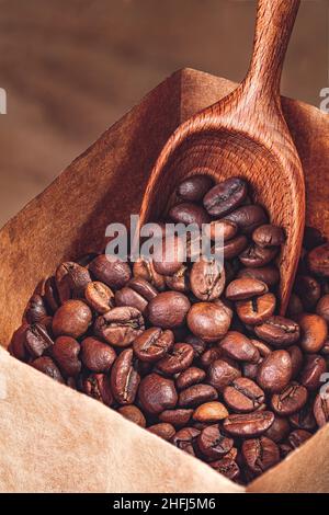 Kaffeebohnen in Papiertüte mit Holzlöffel Stockfoto