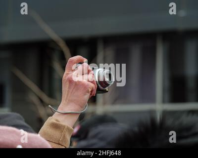 Halten Sie die Hand fest, und nehmen Sie eine Digitalkamera über der Masse auf. Stockfoto