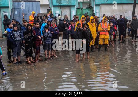 Gaza-Stadt, Palästina. 16th Januar 2022. Palästinenser warten im Flüchtlingslager Jabalia im nördlichen Gazastreifen auf einer überfluteten Straße, um bei starkem Regen gerettet zu werden. Kredit: SOPA Images Limited/Alamy Live Nachrichten Stockfoto