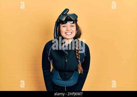 Junge hispanische Mädchen trägt Taucher Neopren Uniform mit einem glücklichen und kühlen Lächeln auf dem Gesicht. Glückliche Person. Stockfoto