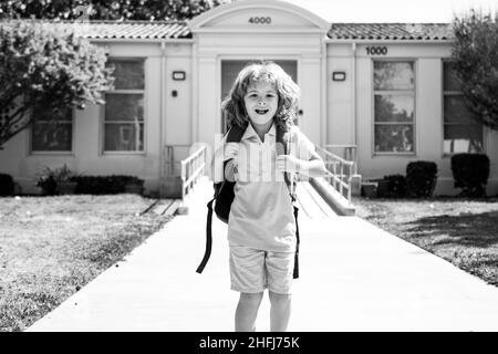 Kinderpuppe mit Rucksäcken im Park in der Nähe der Schule. Schuljunge mit Rucksäcken im Freien. Wissenstag. Schuluniform. Stockfoto