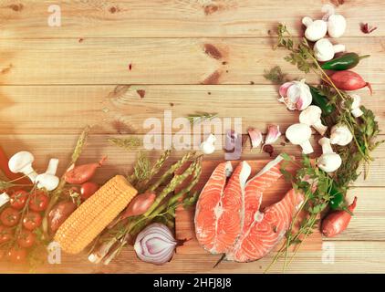 Speiserahmen aus Lachssteaks, Gemüse, Pilzen auf Holzboden Stockfoto