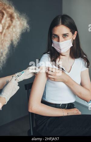 Ärztin in Handschuhen, die die Schulter eines Patienten mit Impfstoff impft. Arzt, der Patienten mit Corona-Virus-Impfstoff-Injektion verabreicht. Pandemieprävention. Antiviral Stockfoto