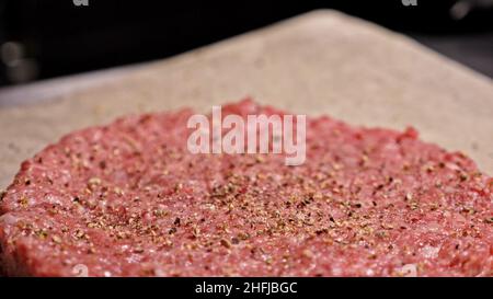 Kochen macht Fleisch Medaillons für Burger. Koch in schwarz Handschuhe macht Schnitzel essen. Die koteletts sind in Stahl Ring in eine noch Medaillon eingeebnet. Stockfoto