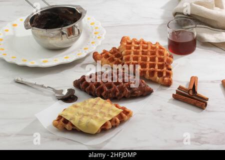 Croisant Waffel mit verschiedenen Topping, Käse, Schokolade, Zucker und Zimt. Craffle ist virales Street Food aus Korea. Ausgewählter Fokus Stockfoto