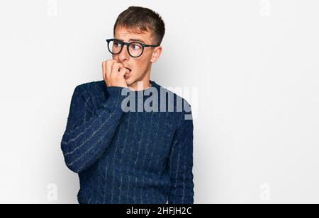 Junge blonde Mann trägt Freizeitkleidung und Brille gestresst und nervös mit den Händen auf den Mund beißende Nägel. Angstproblem. Stockfoto