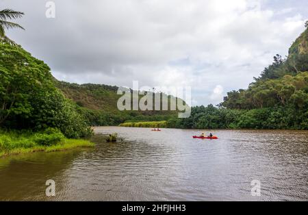 Kauai, Hawaii - 9. Dezember 2021: Malerische tropische Landschaft in der Nähe des Wailua Flusses und des Kamokila Hawaiian Village auf der Kauai Insel, Hawaii. Leute Kajakfahren o Stockfoto
