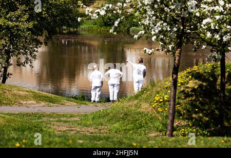 Umea, Norrland Schweden - 10. Juni 2020: Drei Krankenschwestern haben während der Pandemie an einem kleinen See eine Pause Stockfoto