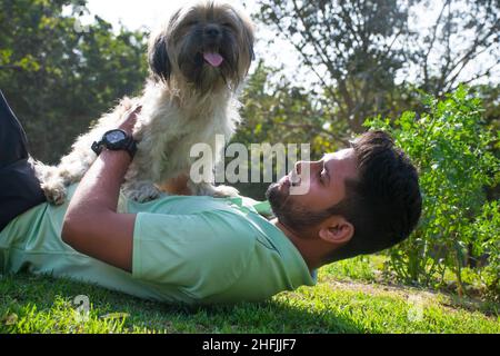 Junger Mann, der im Park mit seinem Hund fetch spielt Stockfoto