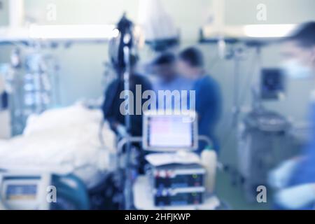 Gruppe von Ärzten neben dem Patientenbett auf der Intensivstation, unfokussierter Hintergrund. Stockfoto