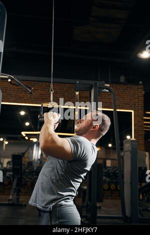 Konzentrierter männlicher Athlet beim Training auf dem Seilzug Stockfoto