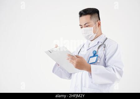 Studio Porträt des Arztes in Schutzmaske Füllung medizinischen Bericht auf Zwischenablage Stockfoto