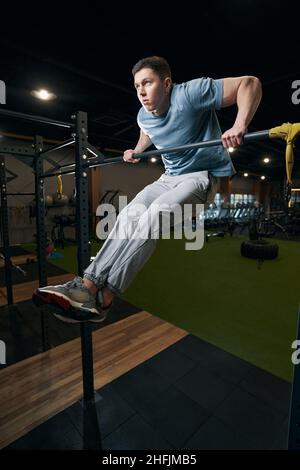 Serious fit junger Mann zieht sich auf horizontale Stange Stockfoto