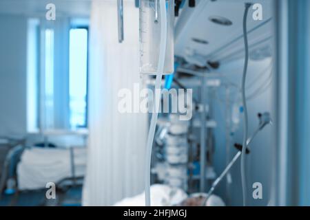 Krankenhausabteilung mit lebenssupprosen Geräten, die an den Komatosen angeschlossen sind, Schlauch in der Bildmitte als Konzept des Bindungsfadens zwischen Patienten Stockfoto