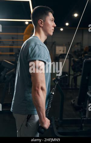 Konzentrierter Athlet, der Kraftübungen an der Seilmaschine durchführt Stockfoto