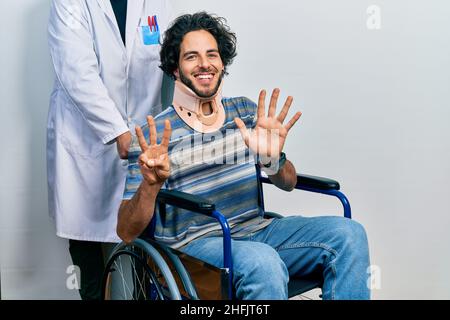 Gutaussehender hispanischer Mann, der auf dem Rollstuhl sitzt und einen Halsband trägt und mit den Fingern Nummer acht nach oben zeigt, während er selbstbewusst und glücklich lächelt. Stockfoto
