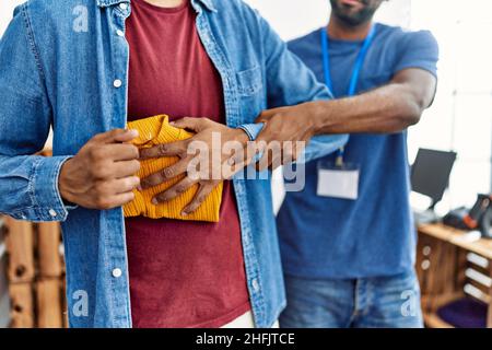 Zwei Männer, Ladenbesitzer und Kundendieb, stehlen Kleidung im Bekleidungsgeschäft Stockfoto