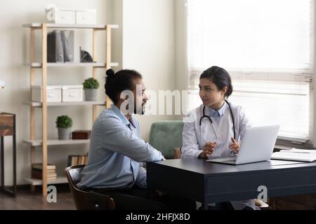 Fokussierter indischer Arzt, der afroamerikanische Patienten konsultiert. Stockfoto