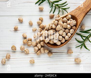 Ungekochte getrocknete Kichererbsen in Holzlöffel auf einem alten Holz Tabelle Stockfoto