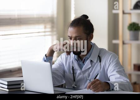 Betont junger afroamerikanischer Arzt, der an eine Problemlösung denkt. Stockfoto