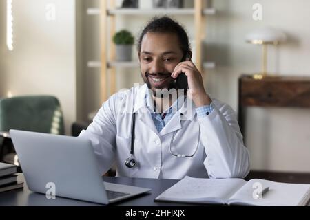 Lächelnder junger afroamerikanischer Arzt, der im Büro multitasking. Stockfoto