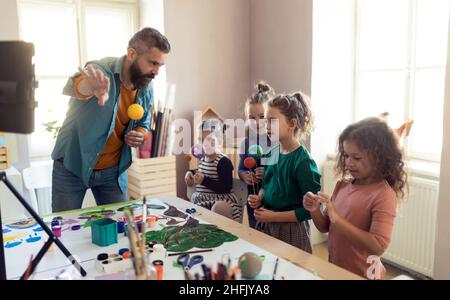 Eine Gruppe von kleinen Kindern, die während des kreativen Kunst- und Bastelunterricht in der Schule an einem Projekt mit dem Lehrer arbeiten. Stockfoto