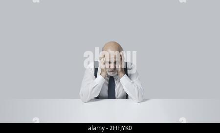 Verzweifelter Geschäftsmann sitzt mit Kopf in den Händen, Stress und Depression Konzept Stockfoto