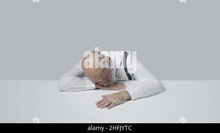 Der traurige Geschäftsmann, der am Schreibtisch schläft, ist depressiv und müde Stockfoto
