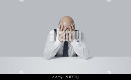 Verzweifelter Geschäftsmann sitzt mit Kopf in den Händen, Stress und Depression Konzept Stockfoto