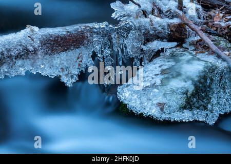 Nahaufnahme von gefrorenen Flussfelsen. Eiszapfen und gefrorene Wasserstrukturen. Stockfoto