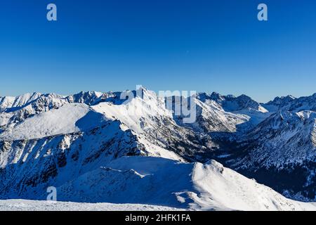 Schneebedeckte und vereisten Wanderwege in der Polnischen Tatra mit Blick auf die umliegenden hohen Gipfel. Stockfoto