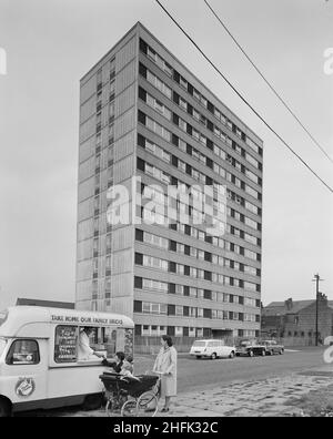 Hornchurch Court, Bonsall Street, Hulme, Manchester, 12/08/1965. Ein kürzlich fertiggestellte mehrstöckige Wohnblock mit „Sectra“-Wohnungen in Hulme, wahrscheinlich Hornchurch Court, mit einer Familie im Vordergrund, die von einem Eiswagen kauft. Sectra&#X2019; war eine französische Stahlschalung für Wohnungen, an der John Laing und Son Ltd 1962 die britischen Rechte erworben haben. Es handelte sich um eine Methode zur Verwendung von präzisionsgefertigten Stahlschalungen für die Platzierung von Strukturbeton in „Tunnelabschnitten“ in Raumteilbreiten und Deckenhöhen. Die Einheiten wurden in Reihen auf speziellen Gleisen mit dem Betonpo verschraubt Stockfoto