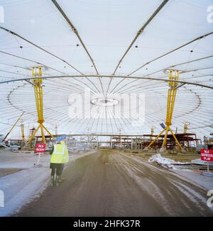 Millennium Dome, Drawdock Road, Greenwich, London, 28/01/1999. Der Blick vom Eingang zum Millennium Dome, entlang der Hauptdurchgangsstraße in Richtung Zentrum, die von allen Baufahrzeugen genutzt wird. Auf beiden Seiten der Strecke befinden sich Schilder, die die Positionen von zwei Exponaten oder Themenbereichen, Body und Serious Play, anzeigen. Stockfoto