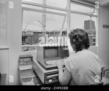 Eastgate Shopping Centre, Southernhay, Basildon, Essex, 20/07/1982. Ein Büroangestellter, der an einem Datapoint 1550-Computer saß, mit Blick durch ein Fenster auf den Bau des neuen Eastgate-Einkaufszentrums. Stockfoto