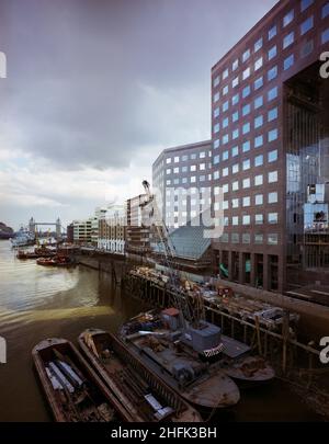 London Bridge City, Southwark, Greater London Authority, 01/04/1986. Blick nach Osten entlang des Südufers der Themse in Richtung Tower Bridge, zeigt rechts den London Bridge City Komplex mit Lastkähne im Vordergrund. Verschiedene Gebäude in diesem Komplex aus Büros, Wohnungen und Geschäften in der Tooley Street in London Bridge City wurden von Laing Management Contracting für die St Martins Group gebaut, die das ehemalige Hay's Wharf-Gelände am Südufer der Themse neu entwickelte. Die Sanierung des Geländes erfolgte über 2 1/2 Jahre zwischen 1985-1988 und umfasste die No.1 London Bridge, Cottons Stockfoto