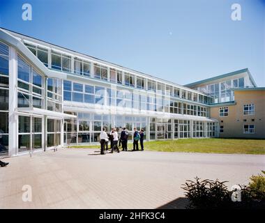 Durrington High School, The Boulevard, Worthing, West Sussex, 18/07/1996. Blick auf eine verglaste Verbindung zwischen Blöcken an der Durrington High School, mit einer Gruppe von Schulkindern draußen. Laing London und South East wurden Anfang 1990 &#X2019;s mit der Durchführung von Entwicklungsarbeiten an der Durrington High School für West Sussex County Council beauftragt. Phase I bestand aus drei neuen Blöcken, in denen wissenschaftliche Labors, Technologie-Workshops, Klassenzimmer, eine Bibliothek und andere Mitarbeiter- und Verwaltungsbereiche untergebracht waren. Phase II umfasste eine neue Sporthalle und einen Speisesaal. Weitere Arbeiten am Standort beinhaltete die Sanierung von Stockfoto