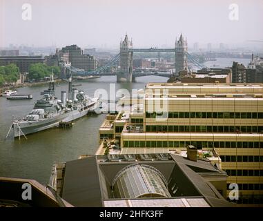 London Bridge City, Southwark, Greater London Authority, 19/06/1986. Blick nach Osten über den London Bridge City Complex, zeigt die HMS Belfast, die an der Themse mit der Tower Bridge dahinter festgemacht ist. Verschiedene Gebäude in diesem Komplex aus Büros, Wohnungen und Geschäften in der Tooley Street in London Bridge City wurden von Laing Management Contracting für die St Martins Group gebaut, die das ehemalige Hay's Wharf-Gelände am Südufer der Themse neu entwickelte. Die Sanierung des Geländes erfolgte über 2 1/2 Jahre zwischen 1985-1988 und umfasste auch die No.1 London Bridge, Cottons, Hays Gallerie und 29-33 Stockfoto