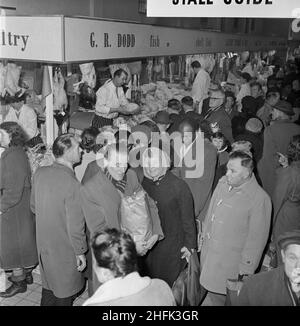 Bull Ring Centre, Birmingham, 23/12/1963. Der Fisch- und Geflügelmarkt im Bull Ring Center ist zur Weihnachtszeit voller Einkaufsbummel. Am 14th. November 1963 wurde der Einzelhandelsmarkt am Bull Ring vom Oberbürgermeister von Birmingham, Alderman Dr. Louis Glass, JP, eröffnet. Der neue Einzelhandelsmarkt ersetzte das alte Markthalle-Gebäude, das ursprünglich 1835 erbaut wurde, aber durch einen Luftangriff im Zweiten Weltkrieg schwer beschädigt wurde. Der allgemeine Teil des neuen Marktes beherbergte 154 Stände, weitere 42 in der separaten Fisch- und Geflügelabteilung. Stockfoto