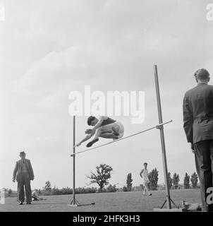 Laing Sports Ground, Rowley Lane, Elstree, Barnett, London, 30/06/1956. Ein Mann, der während eines Sporttages im Elstree Sports Club von Laing einen Hochsprung macht. An diesem Sporttag nahmen Mitarbeiter von Laing und ihre Familien Teil, einige von ihnen reisten von Swindon, Leicester und Dagenham nach Elstree. Der Tag bestand aus verschiedenen Leichtathletik-Veranstaltungen sowie Attraktionen für Kinder, darunter Fahrgeschäfte auf dem Messegelände und Darsteller. Es wurden auch Wettbewerbe für Kunsthandwerk, Kochen, Blumen und Fotografie abgehalten, wobei die Beiträge in einem Festzelt auf dem Fete gezeigt wurden. Stockfoto