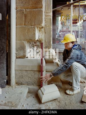 Buttercross, High Street, Ludlow, Shropshire, 21/05/1985. Ein Steinmetz, der während der Renovierungsarbeiten am Buttercross eine Wasserwaage hält, bevor er einen Steinblock ersetzt. Die Renovierungsarbeiten am Buttercross wurden von der Laing-Steinmetzerei durchgeführt, die im August 1984 begann. Das denkmalgeschützte Gebäude der Klasse I, das ursprünglich in den Jahren 1743 bis 46 erbaut wurde, wurde unter Verwendung des lokalen Grinshill-Sandsteins aus Shropshire restauriert. Die Architekten für die Renovierung waren Catterall, Morris &amp; Jaboor aus Shrewsbury. Stockfoto