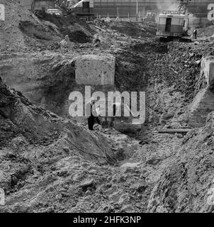 Minories Car Park, 1 Shorter Street, City of London, 12/08/1968. Ein Mann in einem Anzug steht in den Kellergrabungen des Minories Car Park, als zwei Arbeiter hinter ihm Beton mit pneumatischen Bohrern aufbrechen. Laing baute den Minories Car Park zwischen Juli 1968 und Dezember 1969. Der Standort war ein ehemaliger viktorianischer Eisenbahnhof. Die Ziegel- und Betonsockel zweier Drehteller standen den Anhäufungen des Parkplatzes im Weg. Sie wurden schließlich mit kontrollierten Explosionen entfernt. Stockfoto