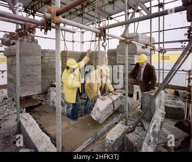 Penrhyn Castle, Llandygai, Bangor, Caernavonshire und Meirionethshire, Wales, 16/05/1984. Laing-Steinmetze manövrieren einen Steinblock im Penrhyn Castle während der Renovierungsarbeiten. Zu der Zeit, als dieses Foto aufgenommen wurde, half die nordwestliche Region von Laing dem National Trust bei der Restaurierung, Renovierung und Generalsanierung einiger ihrer Grundstücke. Das Schloss Penrhyn wurde 1838 erbaut und im Oktober 1983 begannen die von Laing durchgeführten Renovierungsarbeiten, darunter die Entfernung und Reparatur von zwei Dächern, die Entfernung von Brüstungswänden zum Einsetzen neuer bleidächer, die Verfugung von zwei Wänden und Stockfoto