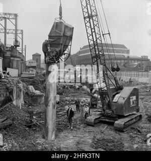 Minories Car Park, 1 Shorter Street, City of London, 11/10/1968. Ein Arbeiter, der oben auf einer Stahlrohrsäule steht und diese mit Beton aus einem Kran-Haufenbehälter auf dem Minories Car Park füllt. Stockfoto