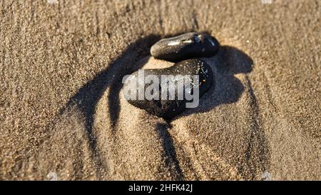 Herzförmiger Stein im Sand des Strandes an der Ostsee. Romantisches Symbol für Verliebte. Kleines Zeichen als Stillleben. Stockfoto